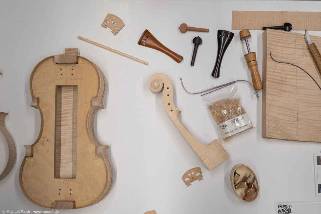 Geige im Bau mit Hölzern, Werkzeugen und Zubehör